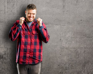 Young handsome man happy and surprised cheering expressing wow gesture