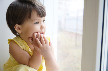 dreaming little girl portrait leans on elbows on window longing for something. thoughtful child thinking about pleasing thoughts