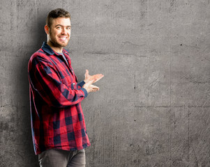 Young handsome man confident and happy with a big natural smile inviting to enter