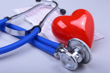 Stethoscope, RX prescription, red heart and assorted pills on white table with space for text.