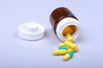Colorful medical pills and capsules on white table with space for text.