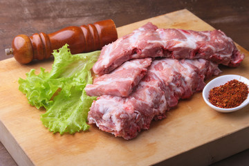 Raw Ribs on a rustic cutting board with salt, pepper and grinder for spices . copy space. Top View.