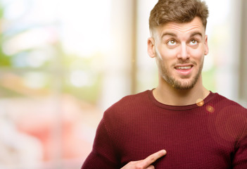 Obraz premium Handsome young man happy and surprised cheering expressing wow gesture pointing up