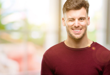 Fototapeta premium Handsome young man blinking eyes with happy gesture