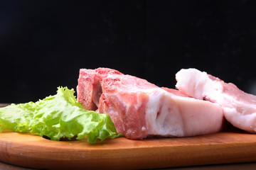 Raw steak on a rustic cutting board with salt, pepper and grinder for spices . Black Background for copy space. Top View.