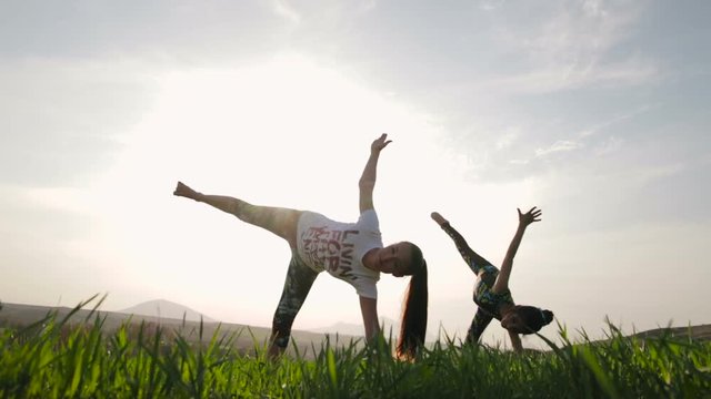 Mother and daughter are engaged in yoga at sunset. Slow motion