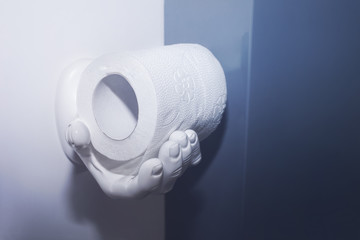 рулон белой туалетной бумаги на держателе в виде человеческой руки