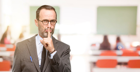 Teacher man using glasses with index finger on lips, ask to be quiet. Silence and secret concept at classroom
