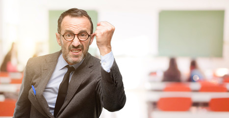 Teacher man using glasses irritated and angry expressing negative emotion, annoyed with someone at...