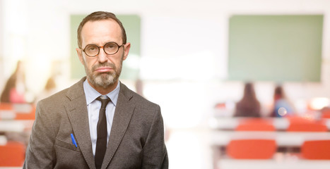 Fototapeta premium Teacher man using glasses with sleepy expression, being overworked and tired at classroom