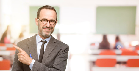 Fototapeta premium Teacher man using glasses pointing away side with finger at classroom