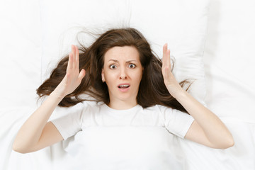 Top view of head of tired brunette young woman lying in bed with white sheet, pillow, blanket....