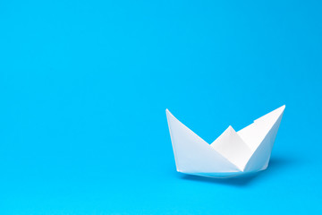 Origami paper boat on blue background
