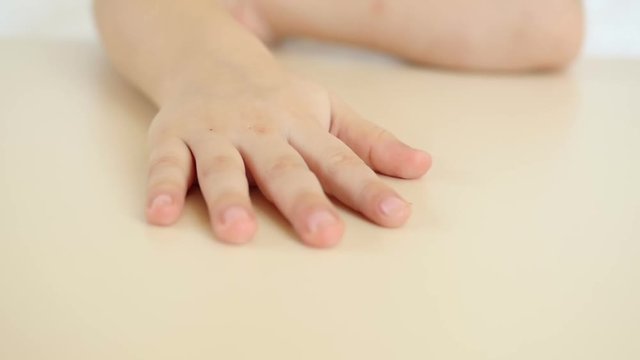 A child shows his hand close-up on a table