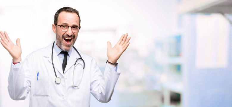 Doctor senior man, medical professional happy and surprised cheering expressing wow gesture at hospital