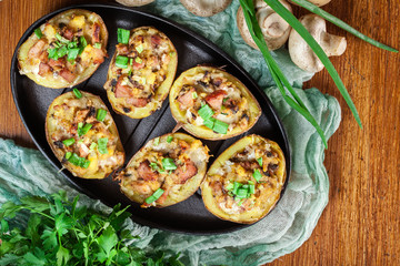 Baked potatoes in jacket stuffed with bacon, mushrooms and chees