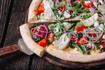 Sliced vegeterian pizza and spatula on wood background