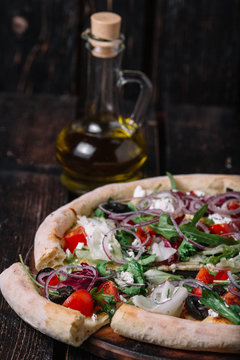 Pizza with one slice and a bottle of olive oul on wood backgroun