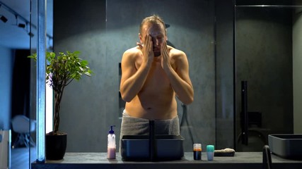 Young man washing face in bathroom

