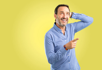Handsome middle age man pointing away side with his finger
