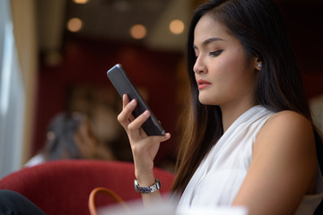 Fototapeta na wymiar Young beautiful Asian businesswoman relaxing at the coffee shop