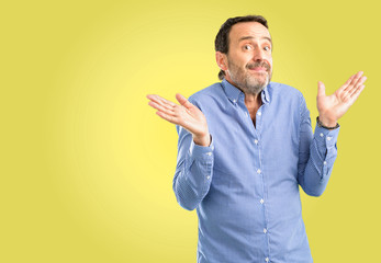 Handsome middle age man doubt expression, confuse and wonder concept, uncertain future shrugging...