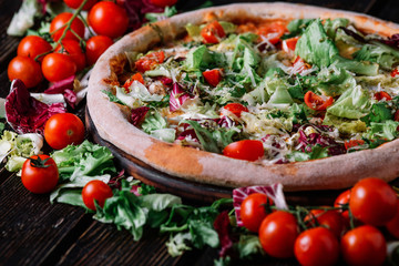 Pizza with chicken, salad and chery tomatoes on wood background