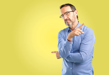 Handsome middle age man pointing away side with his finger