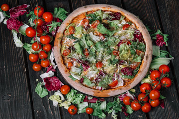 Whole pizza on wood background. Top view