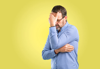 Handsome middle age man stressful keeping hands on head, tired and frustrated