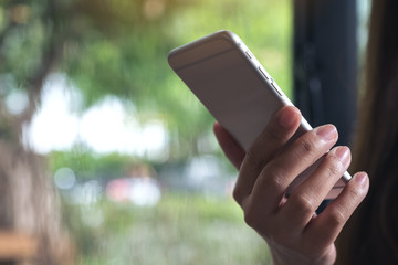 Closeup image of a woman holding , using and looking at smart phone