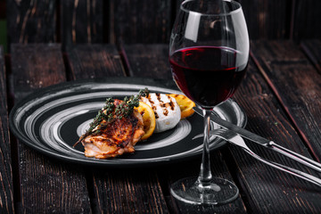 Baked Camembert with caramelized orange and grilled chicken on wood background. Glass of red wine on the table