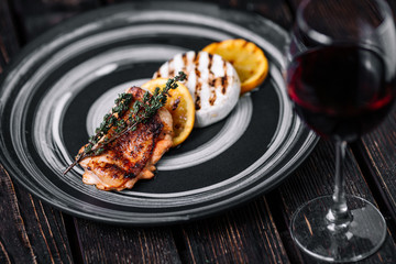 Baked Camembert with caramelized orange and grilled chicken on wood background.