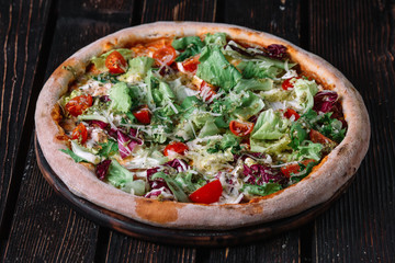 Pizza with salad on wood background