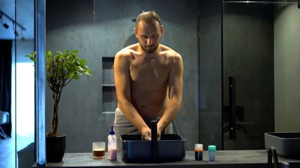 Young man washing his hands in bathroom sink 
