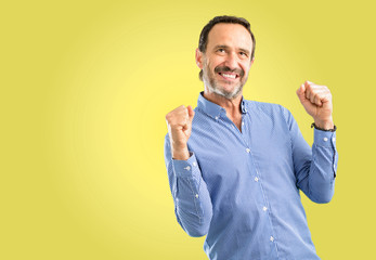 Handsome middle age man happy and excited celebrating victory expressing big success, power, energy...