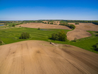 aerial view of a modern tractor plowing a dry field in spring and prepares it for sowing