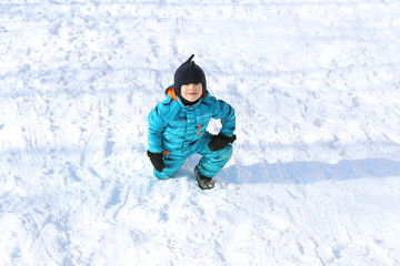 Fototapeta na wymiar 5 years little boy in blue warm overall outdoors in winter