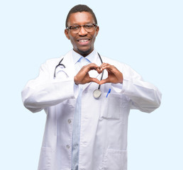 Young black doctor, medical professional happy showing love with hands in heart shape expressing...