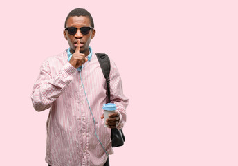 African black man student with index finger on lips, ask to be quiet. Silence and secret concept