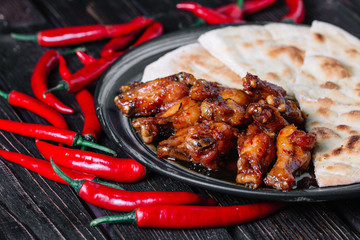 Juicy fried chicken wings with flatbread and chilli peppers