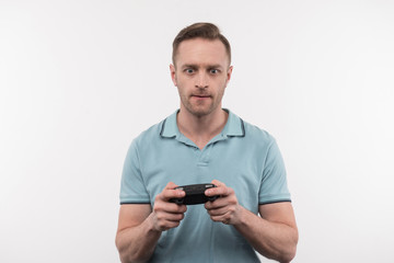 Pleasant entertainment. Handsome nice man holding a game console while playing video games