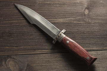 Hunting knife on a wooden background