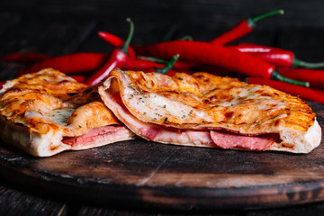 Cutted Spicy Calzone - Stuffed Pizza with chilli peppers on wood