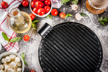 Homemade pasta pizza italian food ingredient on dark rusty table with flour, olive oil, basil, tomatoes and kitchen accessories top view