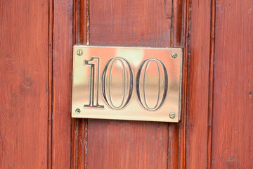 House number 100 brass sign on door