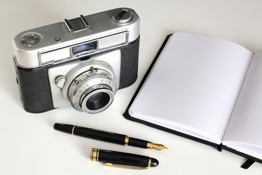 Vintage camera, pen and notebook for the nostalgic journalist and graphic reporter. Empty copy space for Editor's text.