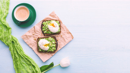 breakfast bruschetta with avocado and spinach and poached egg. with a cup of coffee