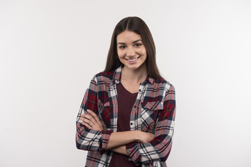 Positive emotions. Happy young woman smiling to you while standing with her arms crossed