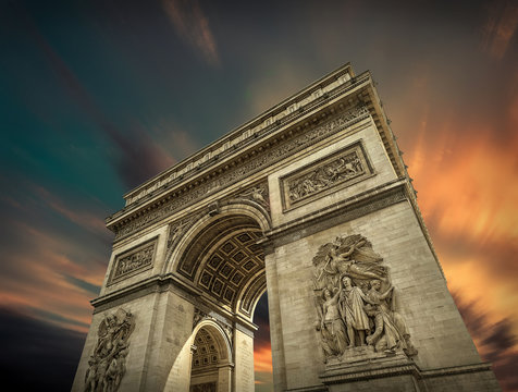 Arc de Triomphe in Paris under sky with clouds. 